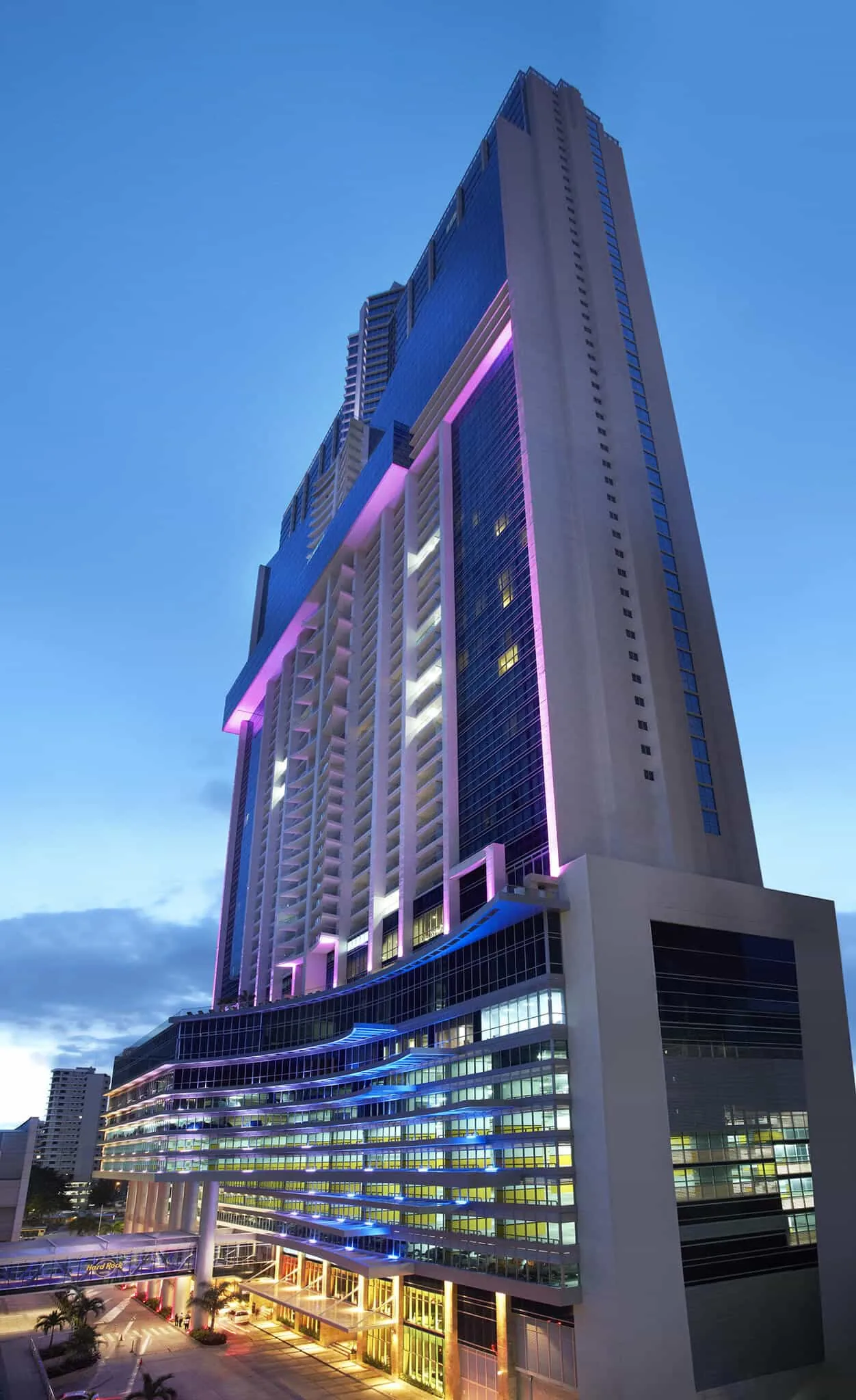 The Hotel Megápolis tower in Panama City at dusk, its facade lit in magenta and blue